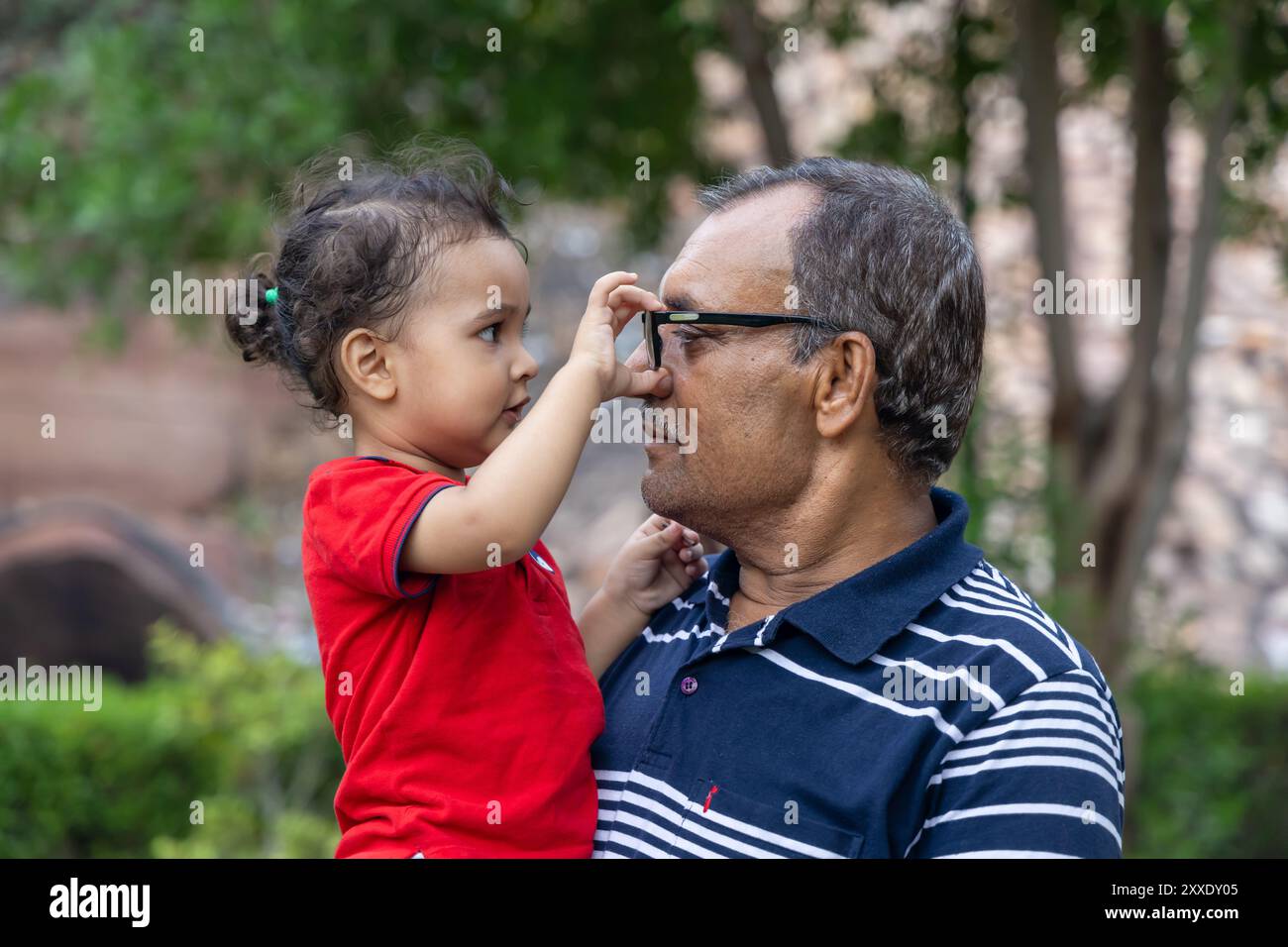 Petit-fils jouant avec les lunettes de grand-père au crépuscule à Park Banque D'Images