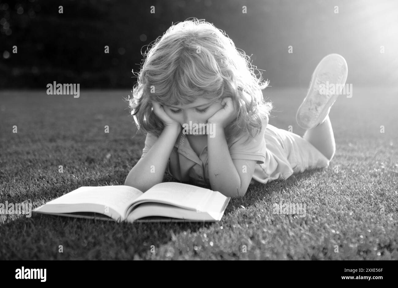 Enfants intelligents.Garçon lisant le livre d'intérêt dans le jardin.L'été s'amuser.Adorable garçon allongé sur l'herbe lisant un livre pour enfants.Concept de l'apprentissage des enfants, l'étude Banque D'Images