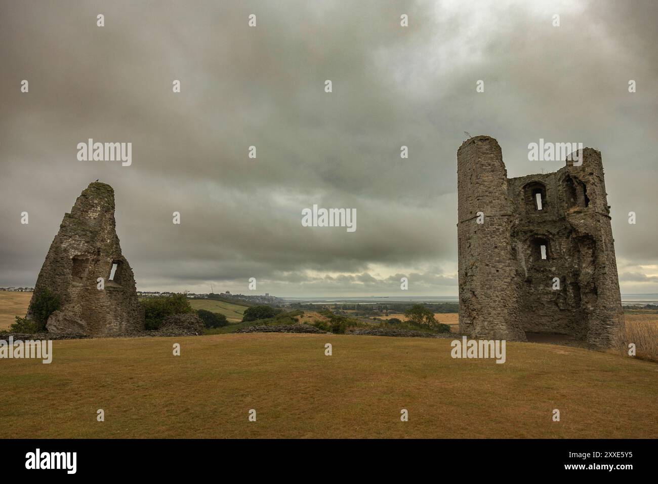 Hadleigh Castle, Royaume-Uni. 24 août 2024. L'image montre les vestiges altérés d'un château en pierre ou d'une forteresse situé sur une colline herbeuse sous un ciel nuageux. Deux tours cylindriques et des murs partiels suggèrent des origines médiévales. Le paysage environnant comprend des champs ouverts et des arbres lointains, évoquant un sentiment d'endurance historique et d'isolement rural. Commencez votre week-end de vacances au château de Hadleigh, surplombant l'estuaire de la Tamise. Penelope Barritt/Alamy Live News Banque D'Images