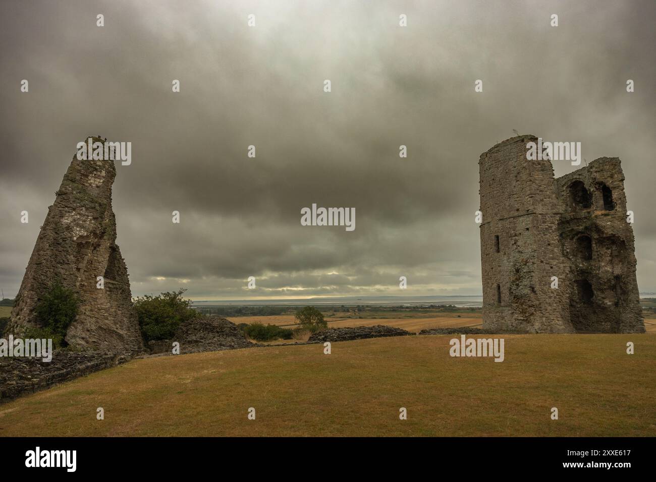 Hadleigh Castle, Royaume-Uni. 24 août 2024. Ruines d'une ancienne structure en pierre dans un champ herbeux sous un ciel nuageux. Un vestige de mur déchiqueté se dresse à gauche, tandis qu'une tour plus intacte avec des ouvertures de fenêtre s'élève à droite. Le vaste paysage et la spectaculaire couverture nuageuse évoquent un sentiment de mystère historique et d'isolement. Commencez votre week-end de vacances au château de Hadleigh, surplombant l'estuaire de la Tamise. Penelope Barritt/Alamy Live News Banque D'Images