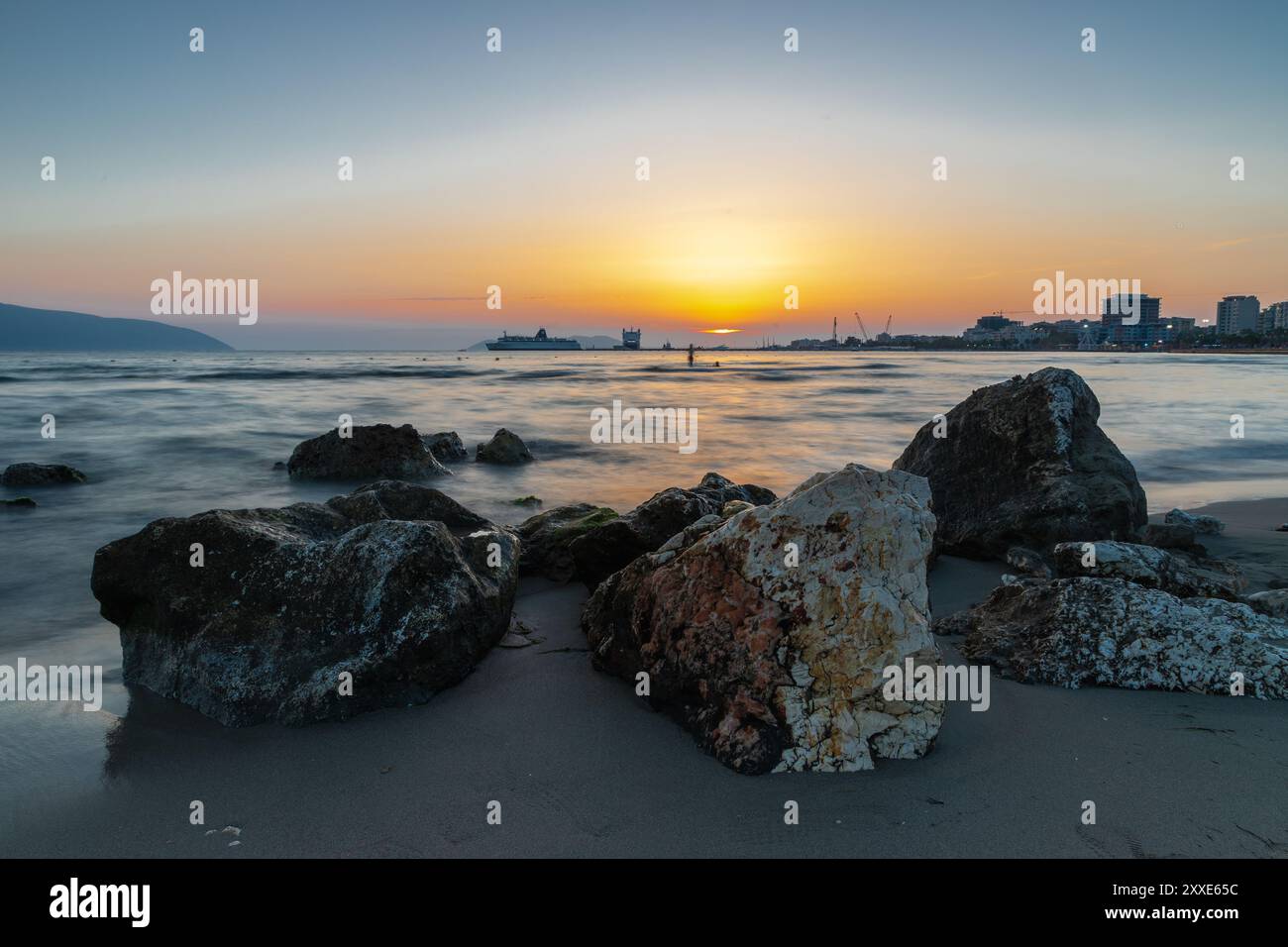 Coucher de soleil sur la plage près de la ville de Vlorë en Albanie, qui s'étend sur la baie de Vlorë et est entouré par les contreforts des montagnes Ceraunian Alo Banque D'Images