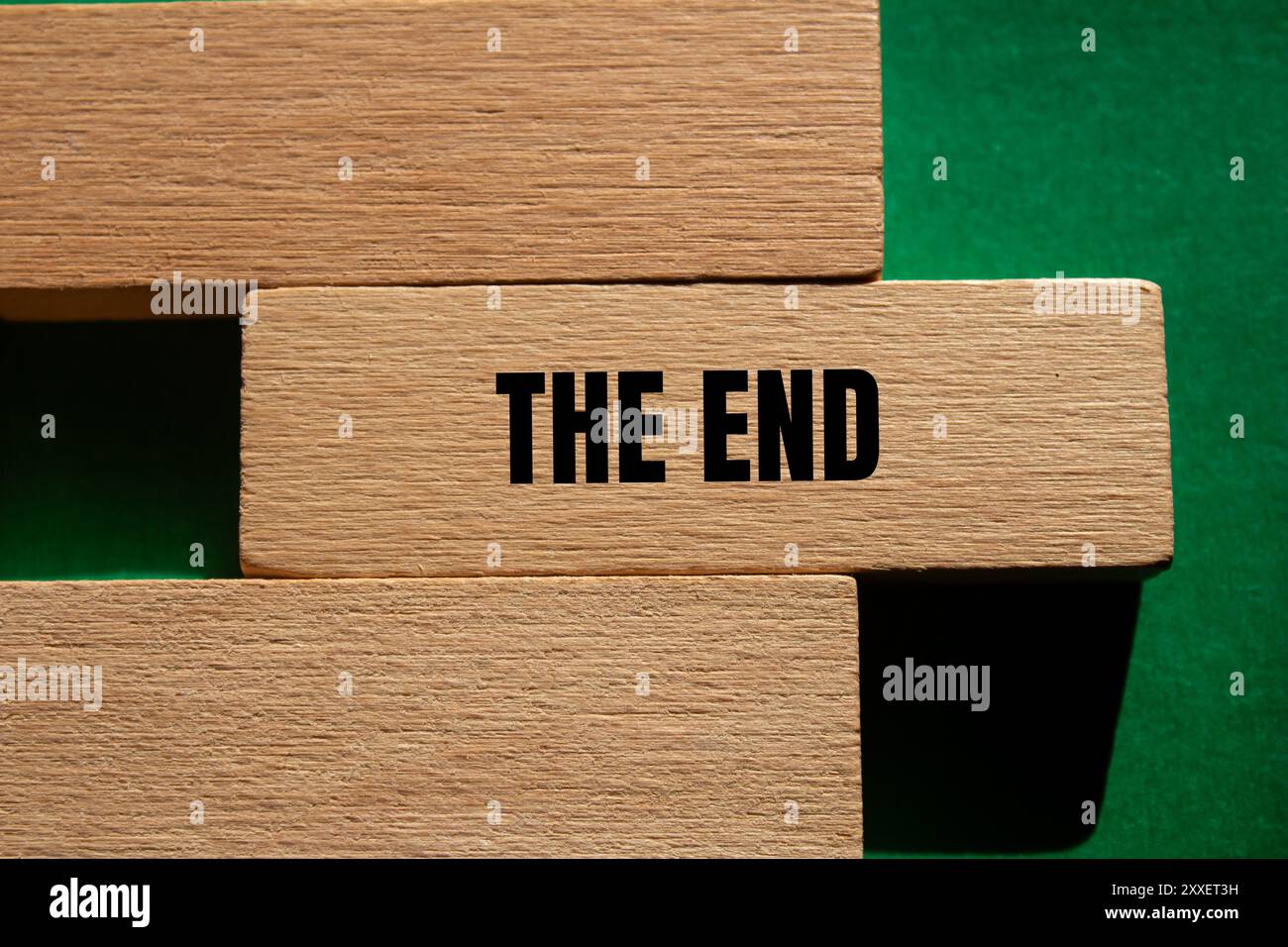 Le message de fin écrit sur bloc de bois avec fond vert. Conceptuel le symbole de fin. Copier l'espace. Banque D'Images