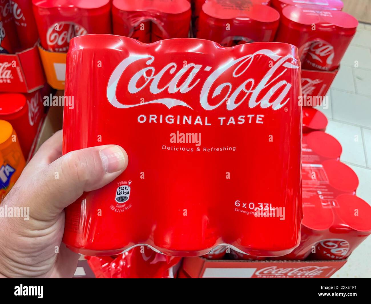 Allemagne Berlin 23 août 2024. Une personne tient un pack de six Coca-Cola original Taste. Les six paquets sont empilés en une rangée Banque D'Images