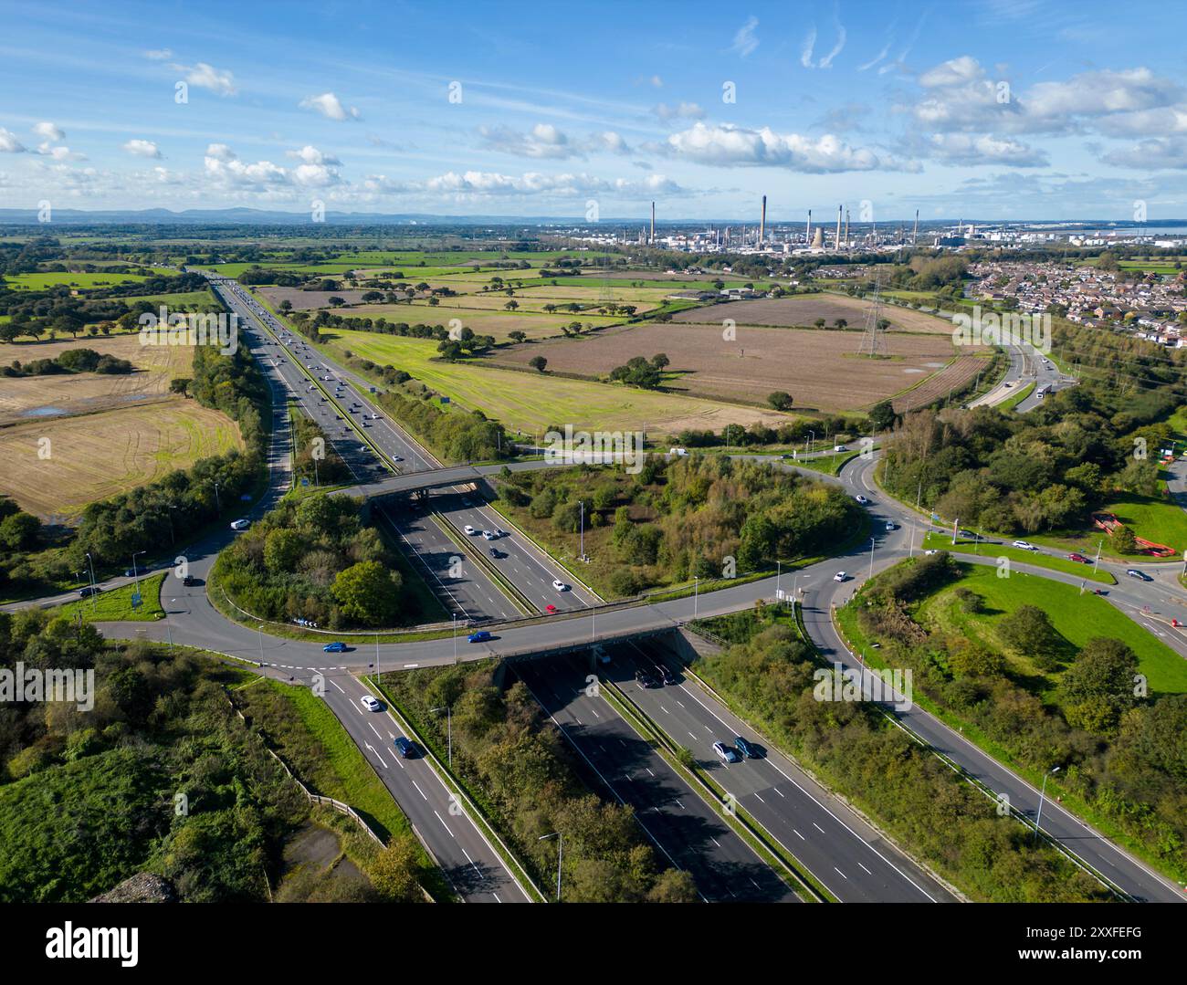 Trafic sur l'autoroute M56 à la jonction 14, Helsby avec la raffinerie de pétrole Stanlow en arrière-plan, Cheshire, Angleterre Banque D'Images