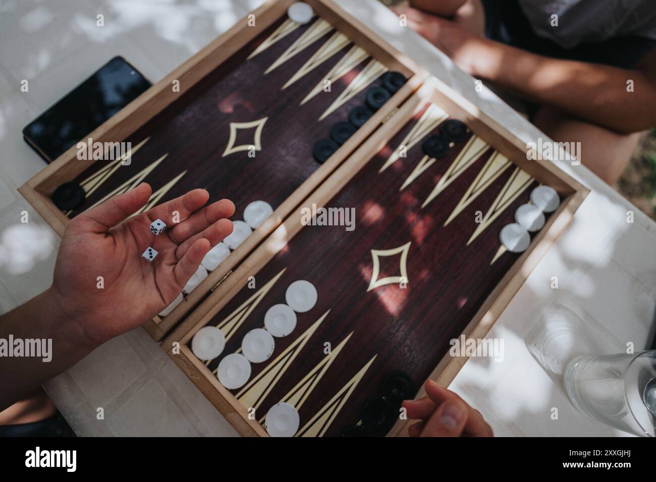 Les mains roulent des dés dans la configuration de jeu de backgammon en plein air Banque D'Images