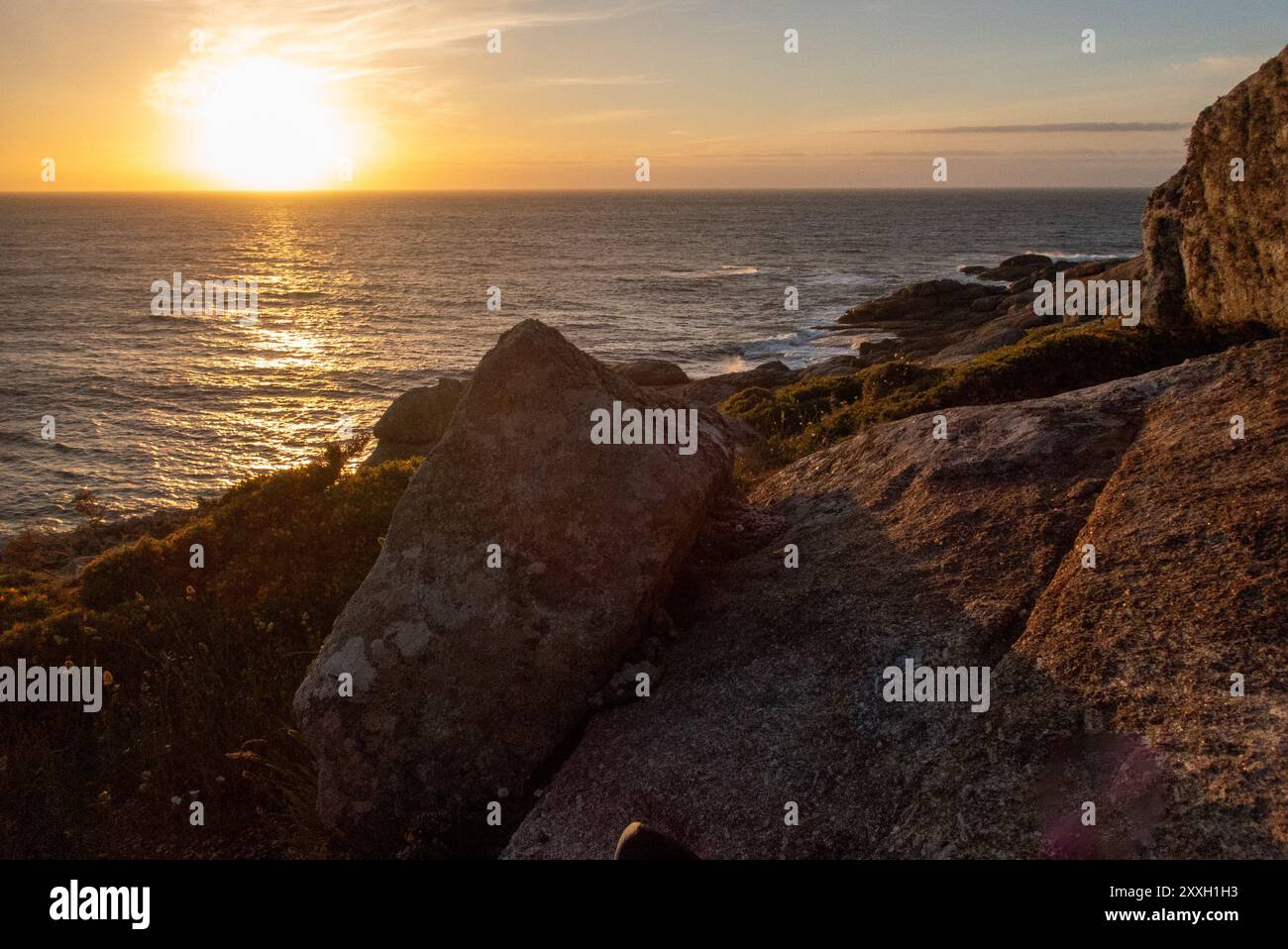 Coucher de soleil sur la côte rocheuse de Muxia surplombant l'Atlantique. Le petit port sur la côte galicienne est l'un des endroits les plus à l'ouest de l'Espagne et un arrêt final populaire pour les pèlerins sur le Camino de Santiago. Banque D'Images