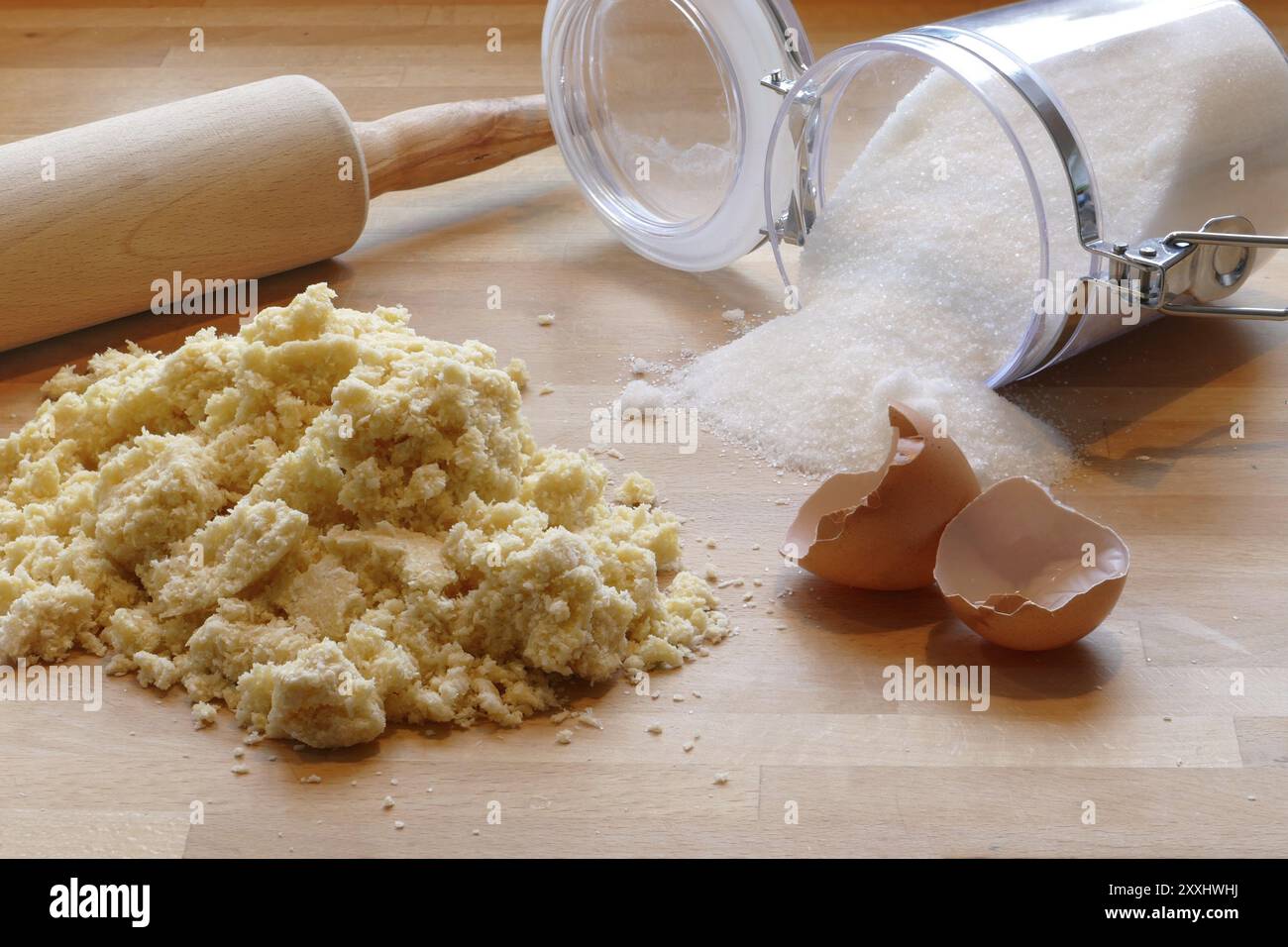 Scène de cuisson à la maison avec rouleau à pâtisserie, pâte, sucre et coquilles d'oeufs vides sur une table en bois Banque D'Images
