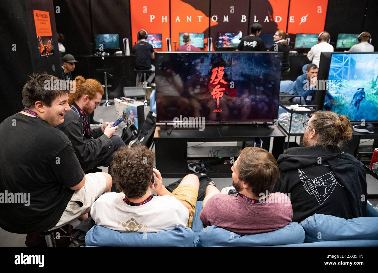 Cologne, Allemagne. 21 août 2024. Les gens essaient Phantom Blade au stand de S-GAME lors de la gamescom 2024 à Cologne, en Allemagne, le 21 août 2024. La gamescom en cours, qui se considère comme le plus grand événement de jeux vidéo au monde, offre une occasion unique aux développeurs de jeux et aux fans de réseauter et d'explorer les dernières tendances de l'industrie du jeu vidéo, avec les organisateurs désireux d'avoir plus de partenaires chinois à l'avenir. L’événement a ouvert ses portes aux visiteurs mercredi avec un nombre record de plus de 1 400 exposants de 64 pays. Crédit : Zhang Fan/Xinhua/Alamy Live News Banque D'Images