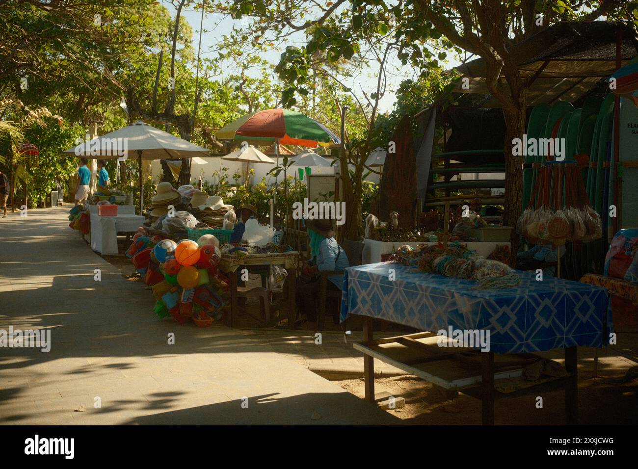 Stalle souvenir vendant des articles tels que des accessoires, bracelets, chapeaux, tissus, jouets pour enfants, et la location de planches de surf par des vendeurs locaux à la plage Banque D'Images