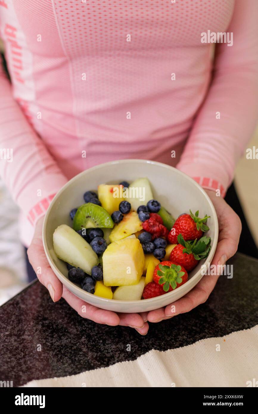 Image portrait d'un gros plan d'une femme tenant un bol de fruits d'été sains et nutritifs incluant fraises, bleuets, melon et kiwi Banque D'Images