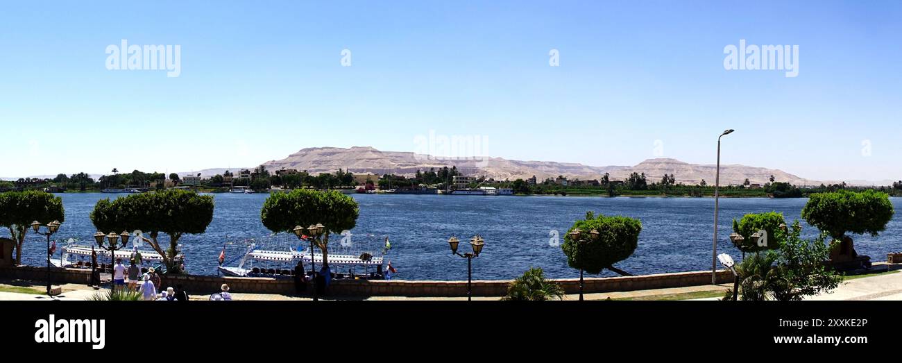 Les visiteurs se réjouissent d'une journée ensoleillée alors qu'ils traversent l'emblématique fleuve du Nil à Louxor, en Égypte, entouré d'une beauté naturelle époustouflante le long de la promenade. Banque D'Images