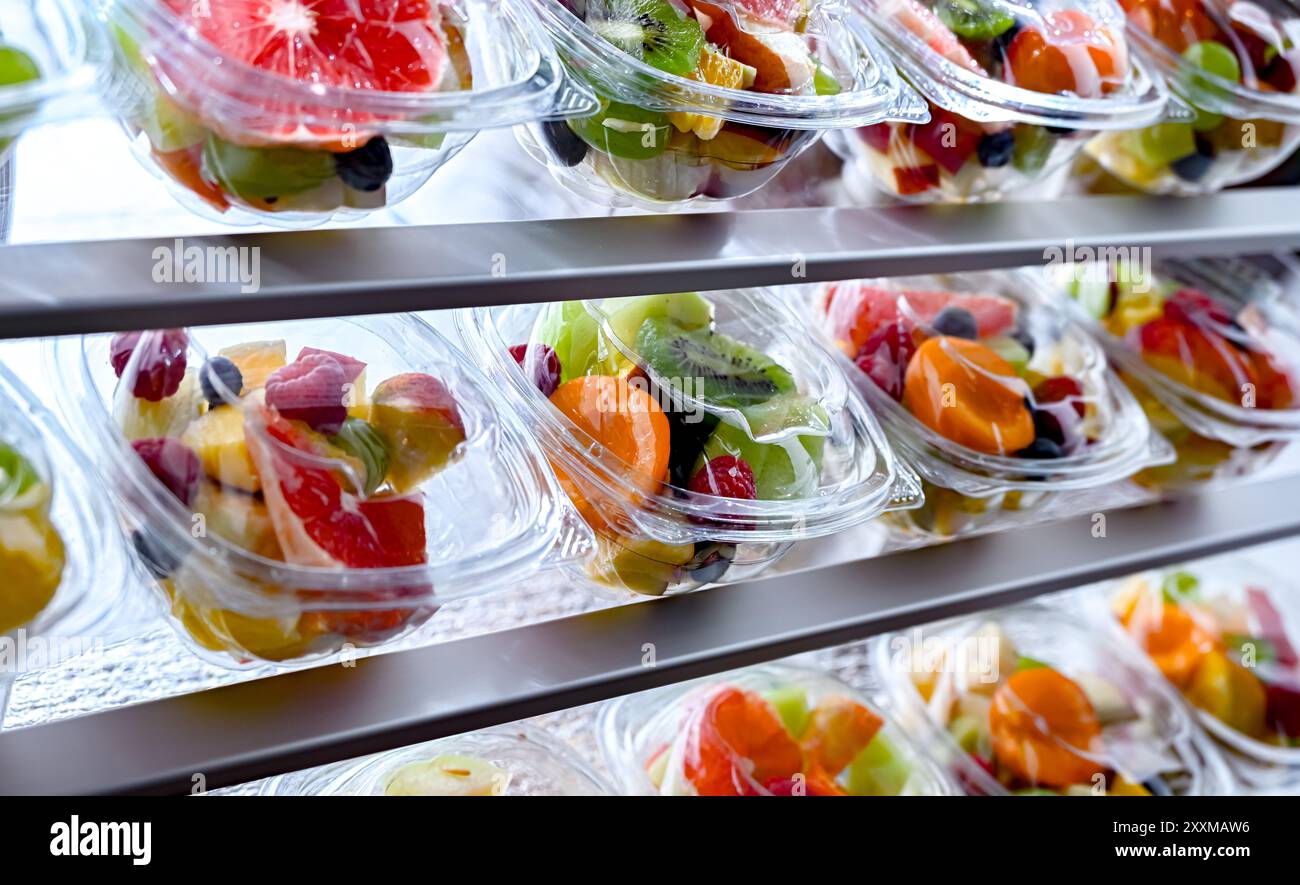 Boîtes en plastique avec salades de fruits préemballées, mises en vente dans un réfrigérateur commercial Banque D'Images