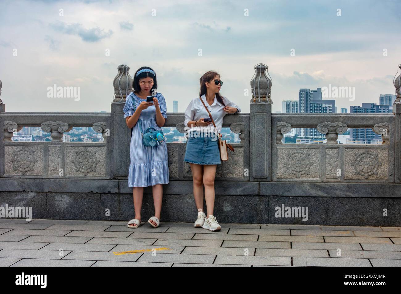 Un couple de dames asiatiques se tiennent contre un mur au niveau supérieur du complexe du temple bouddhiste Kek Lok si à Penang, en Malaisie. Banque D'Images