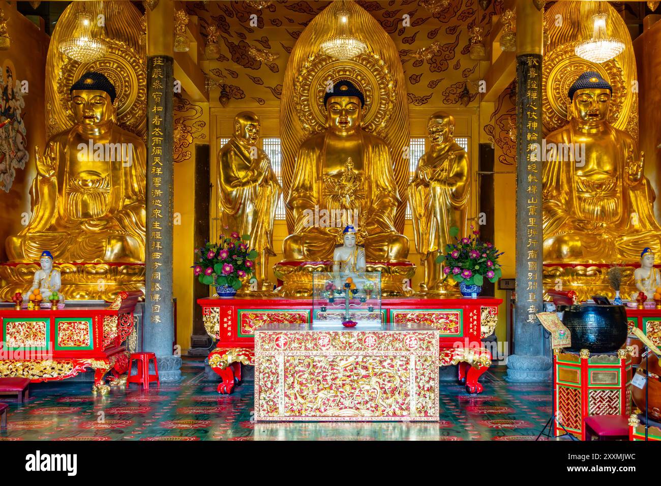 Trois statues dorées de Bouddha sont assis derrière un autel dans un sanctuaire au temple bouddhiste Tek Lok si à George Town, Penang, Malaisie Banque D'Images