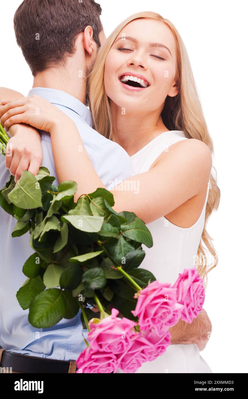 Je t'aime tellement ! Beau jeune couple aimant embrassant tandis que femme tenant un bouquet de roses roses roses et souriant et les deux debout isolé sur BA blanc Banque D'Images