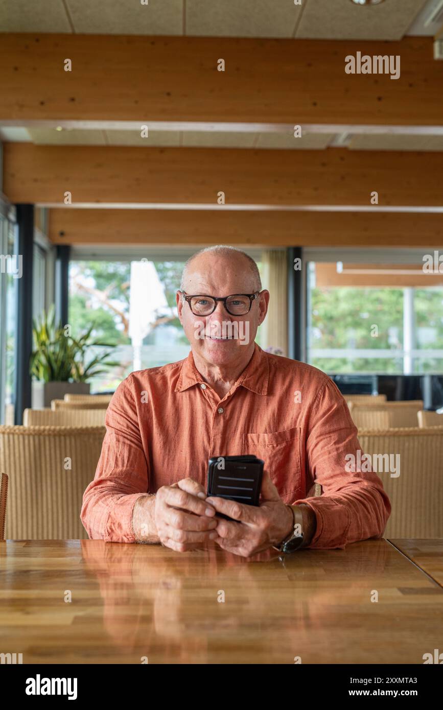 Homme finlandais senior utilisant le téléphone portable dans le restaurant pendant le concept d'automne Banque D'Images