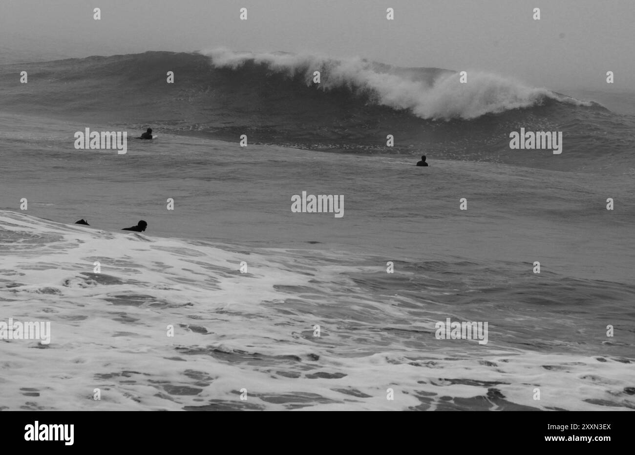 Mar del Plata. Buenos Aires. Argentine. océan brumeux orageux avec peu de surfeurs le jour d'hiver en noir et blanc Banque D'Images
