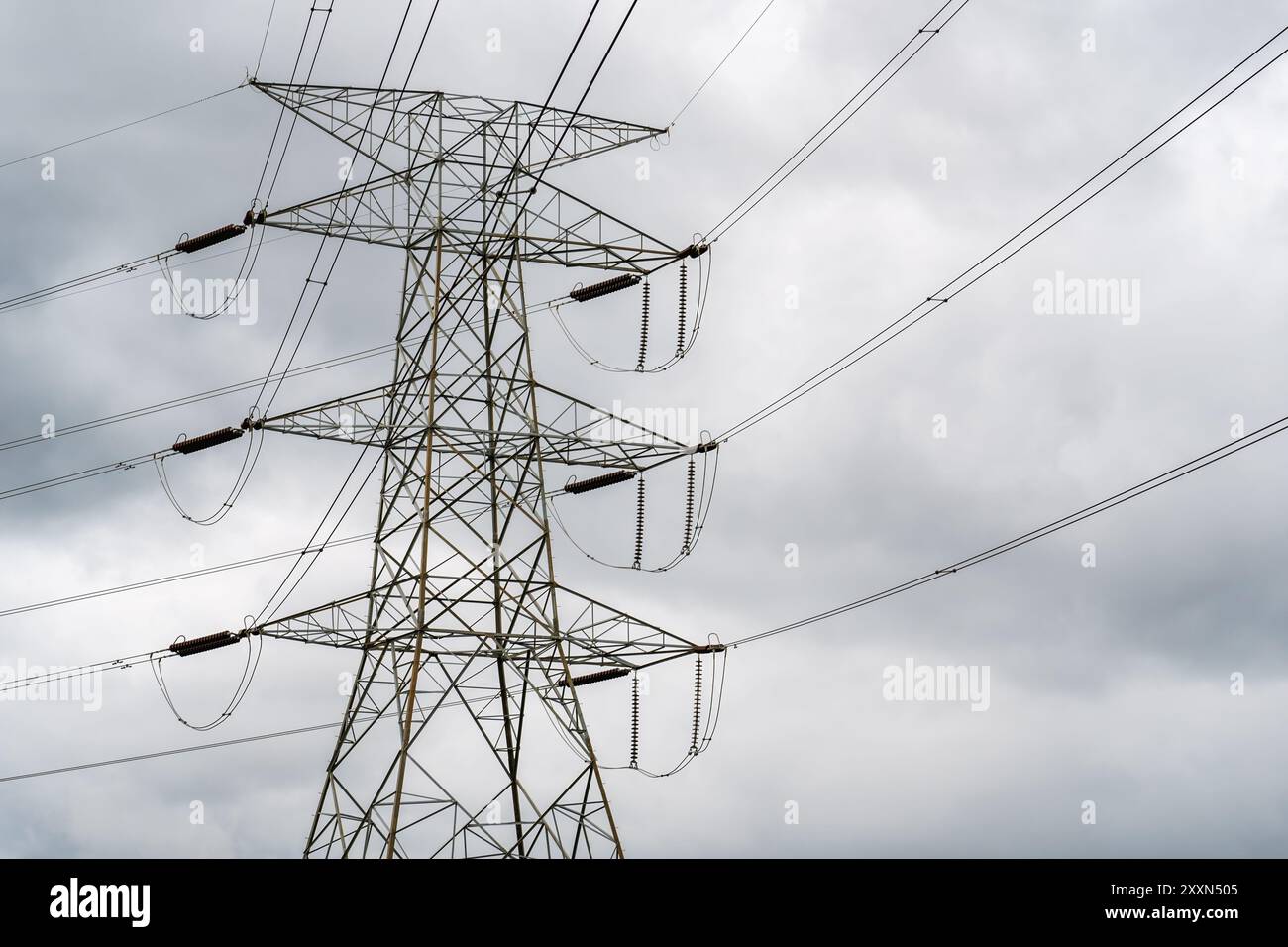 Pylône électrique haut avec des lignes électriques contre un ciel nuageux. Banque D'Images