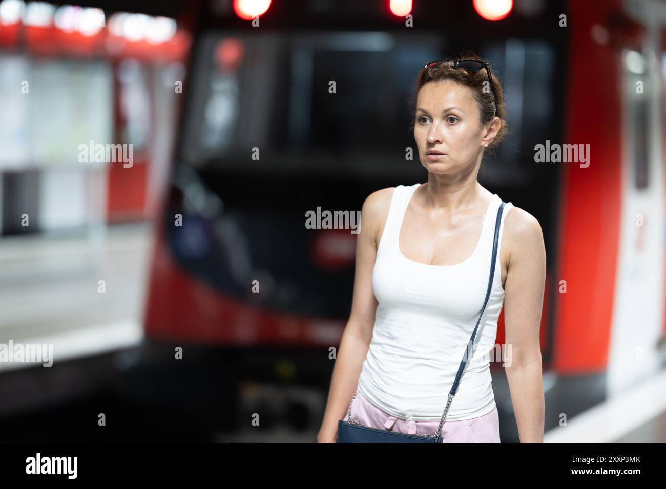 Femme attendant le train de métro à une station de métro Banque D'Images