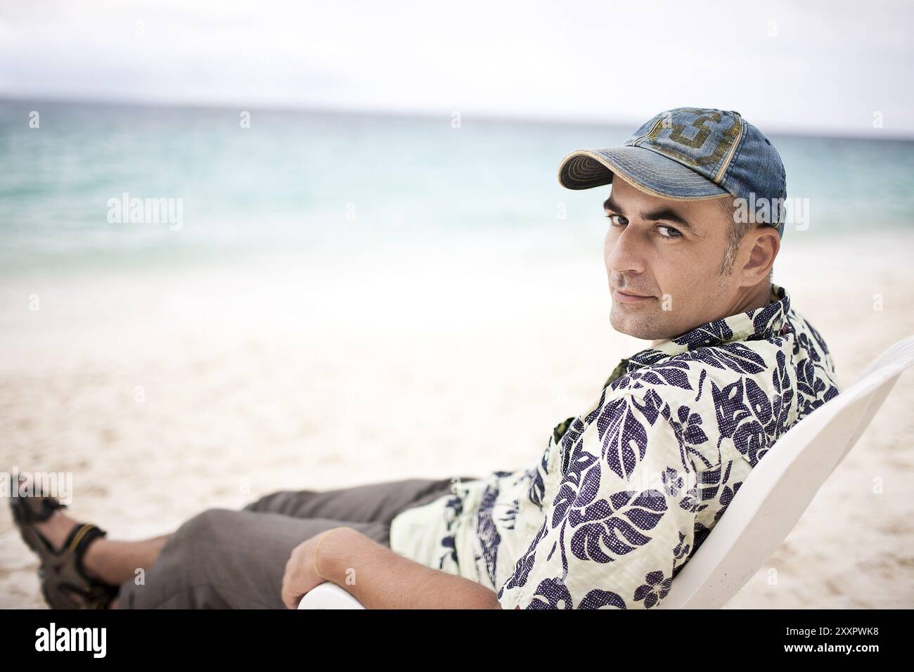 Jeune homme assis près de la mer tropicale Banque D'Images