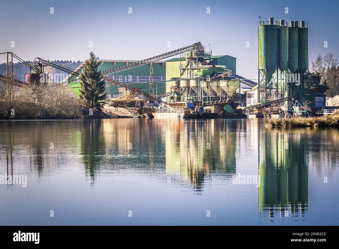 Une usine de béton peint en vert reflété dans un étang de carrière Banque D'Images