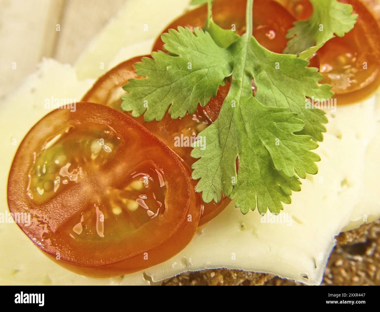 Cracker isolé sur assiette en bois, avec fromage, tomate et persil Banque D'Images