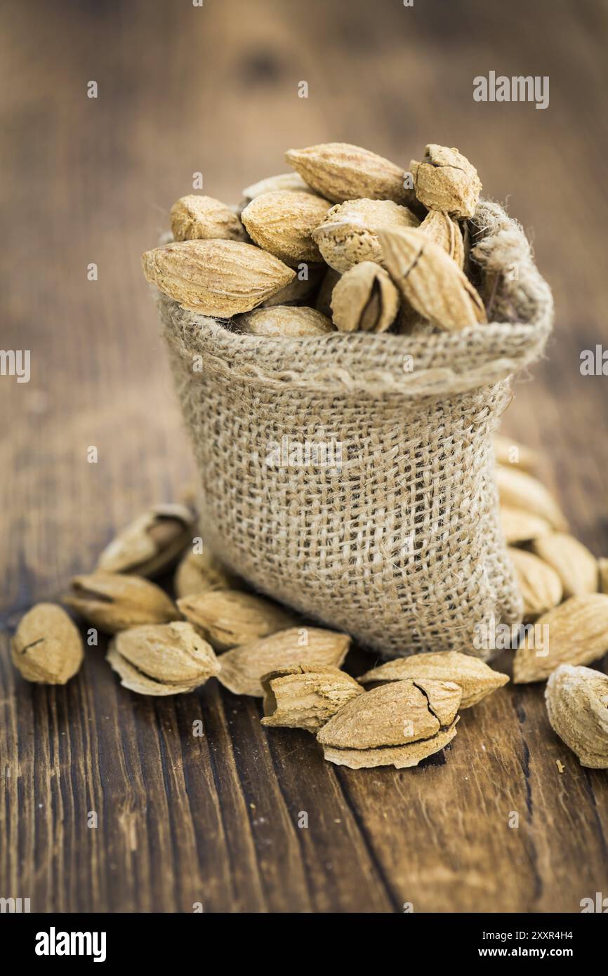 Une vieille table en bois avec amandes torréfiées (dans le shell) comme détaillé close-up shot (selective focus) Banque D'Images