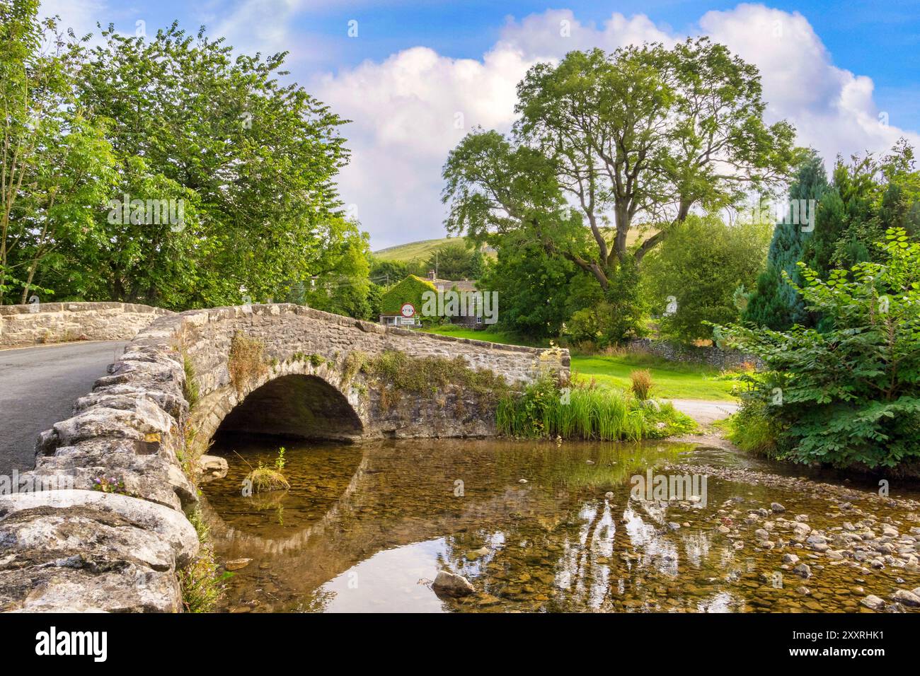 New Bridge, un pont courbé, en pierre, à bosse, ou pont arrière à bosse, à l'origine un pont à cheval de bataille, traversant Malham Beck à Malham, North Yorkshire, Royaume-Uni. Banque D'Images