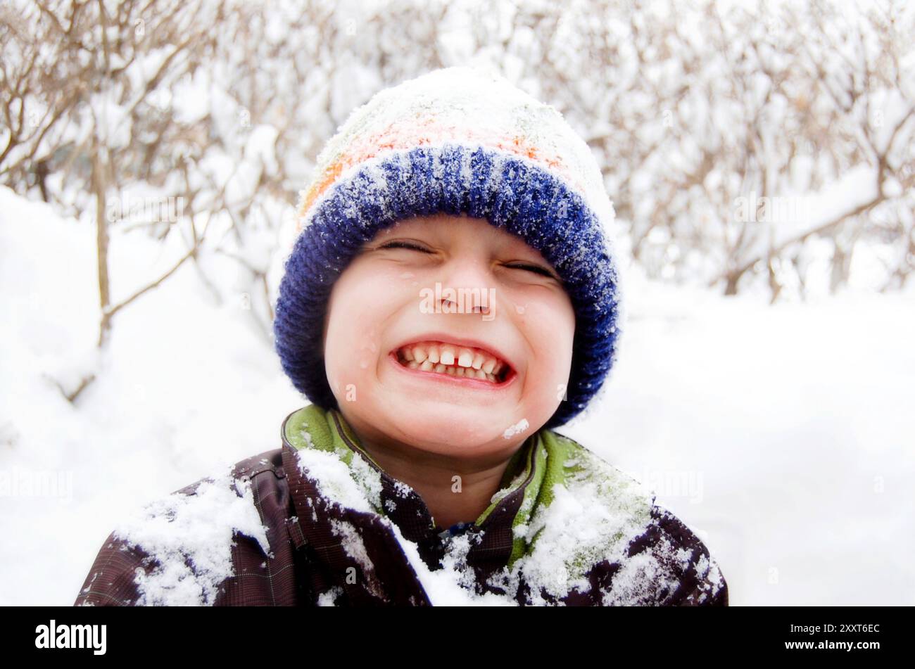 Garçon avec Big Smile jouant et couvert de neige d'hiver Banque D'Images