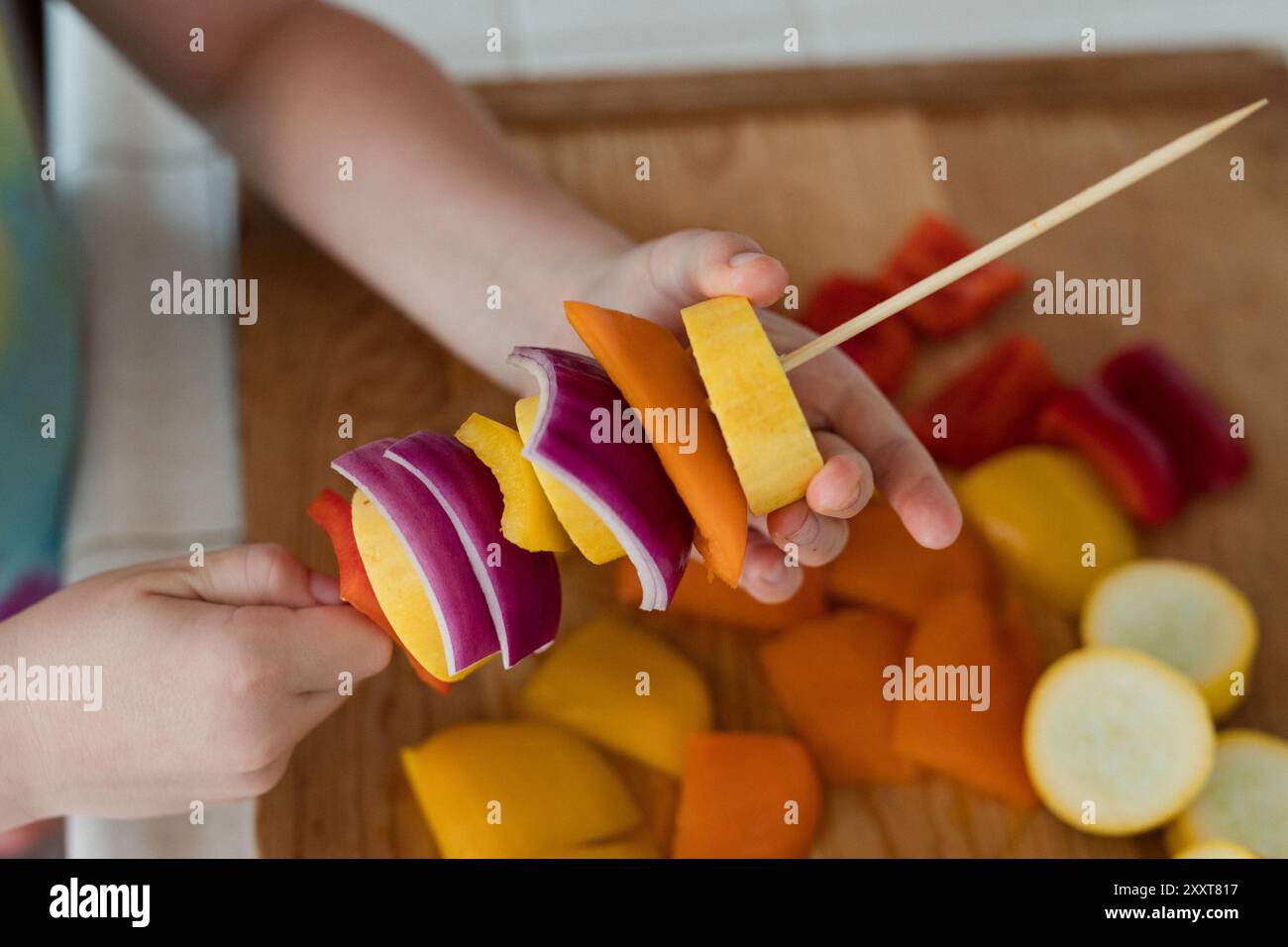 Mains d'enfant assemblant des brochettes de légumes avec des ingrédients colorés Banque D'Images