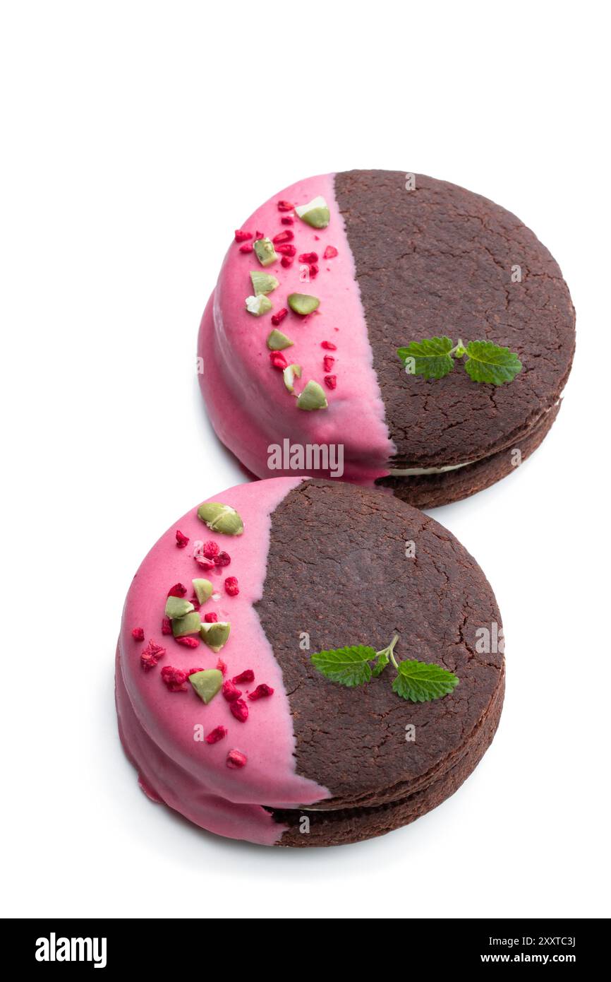 Biscuits au chocolat à la crème et glaçage rose isolés sur blanc Banque D'Images
