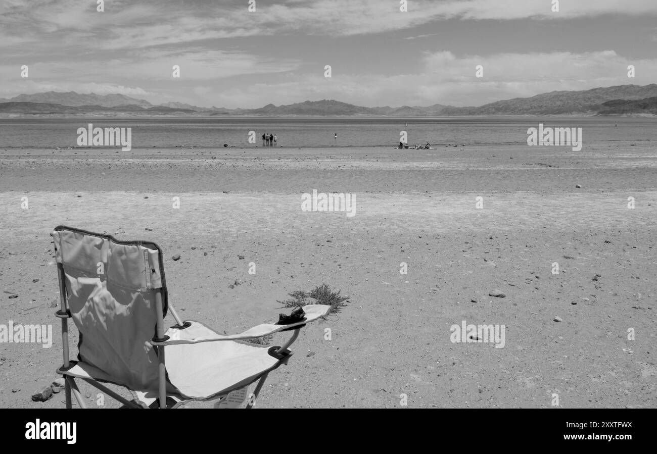 Chaise vide et touristes appréciant la plage de sable à Lake Mead National Recreation Area, Nevada, États-Unis. Banque D'Images