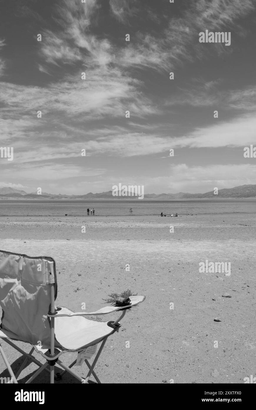 Chaise verte vide et touristes appréciant la plage de sable de Lake Mead National Recreation Area, Nevada, États-Unis. Banque D'Images