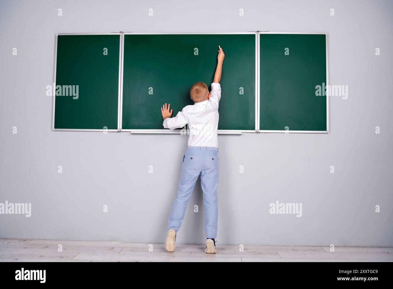 Photo de charmant garçon joli diligent répondant près du tableau vert dans la salle de classe 1er septembre Banque D'Images