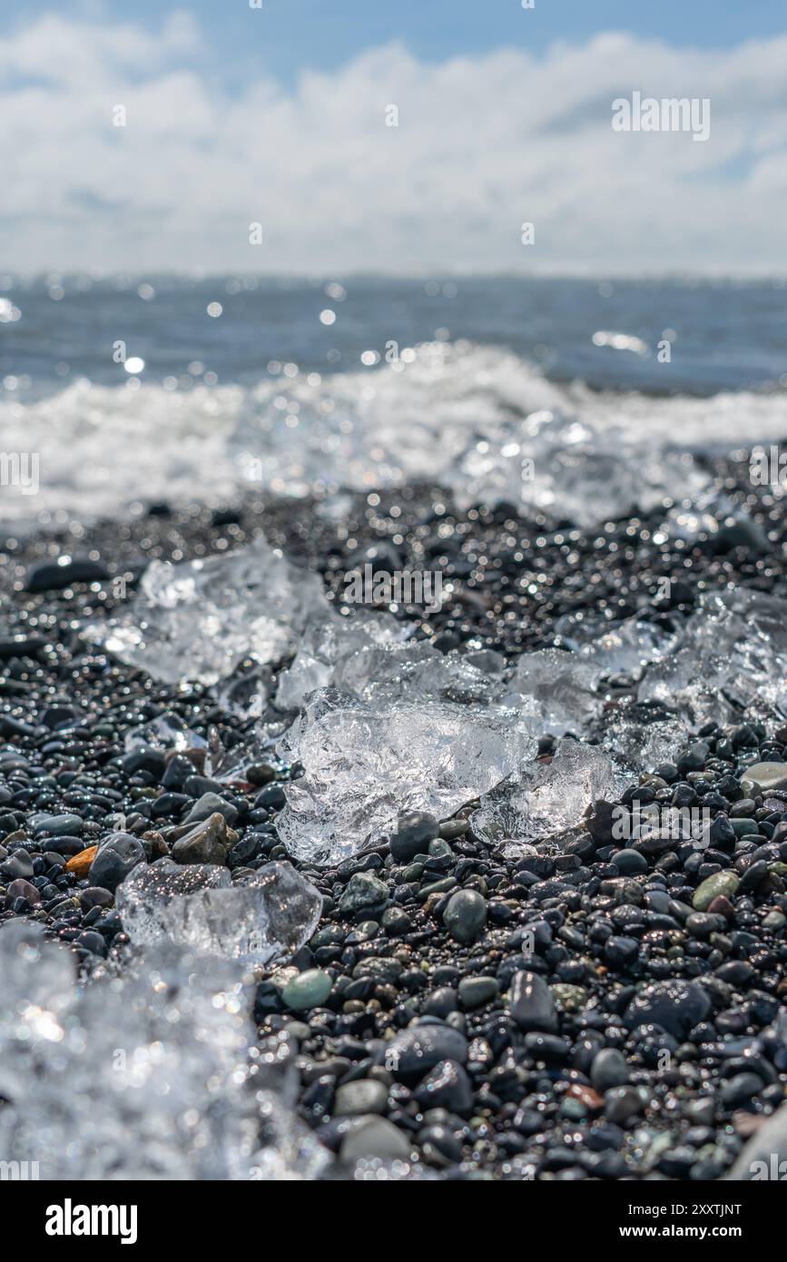 Morceaux de glace et icebergs cassés sur une plage volcanique de sable noir à Diamond Beach en Islande Banque D'Images