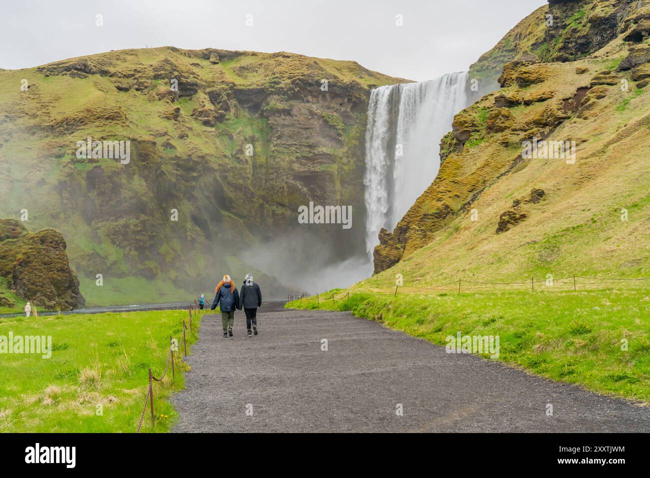 Célèbre cascade de Skogafoss dans le sud de l'Islande avec une vue arrière d'un couple Banque D'Images