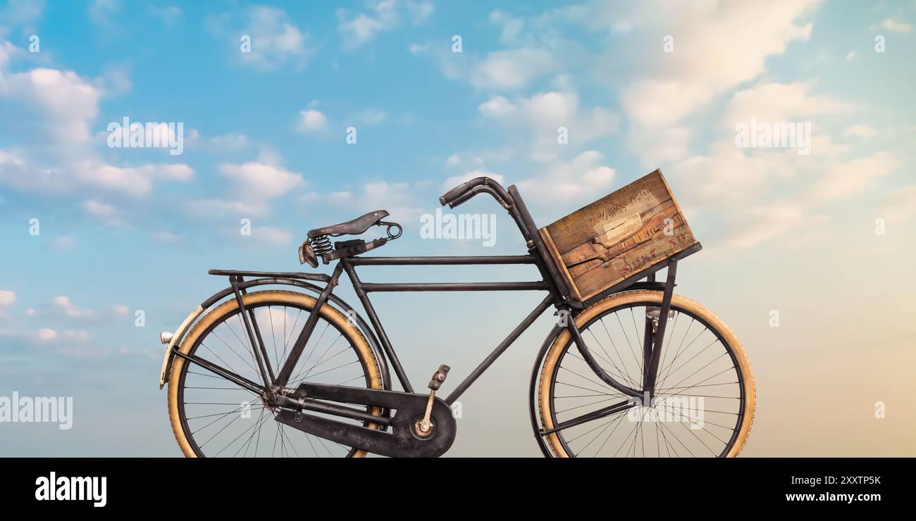 Vélo de transport de marchandises noir vintage avec caisse en bois devant un ciel bleu sombre Banque D'Images