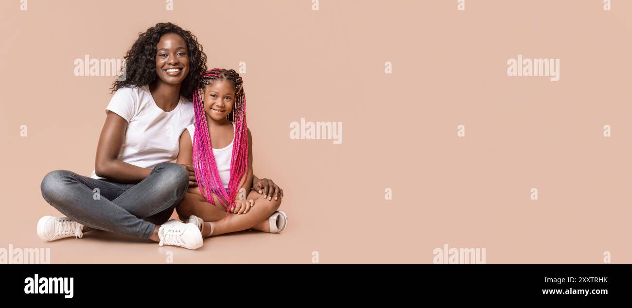 Belle maman noir assis sur le plancher avec son joli fille Banque D'Images