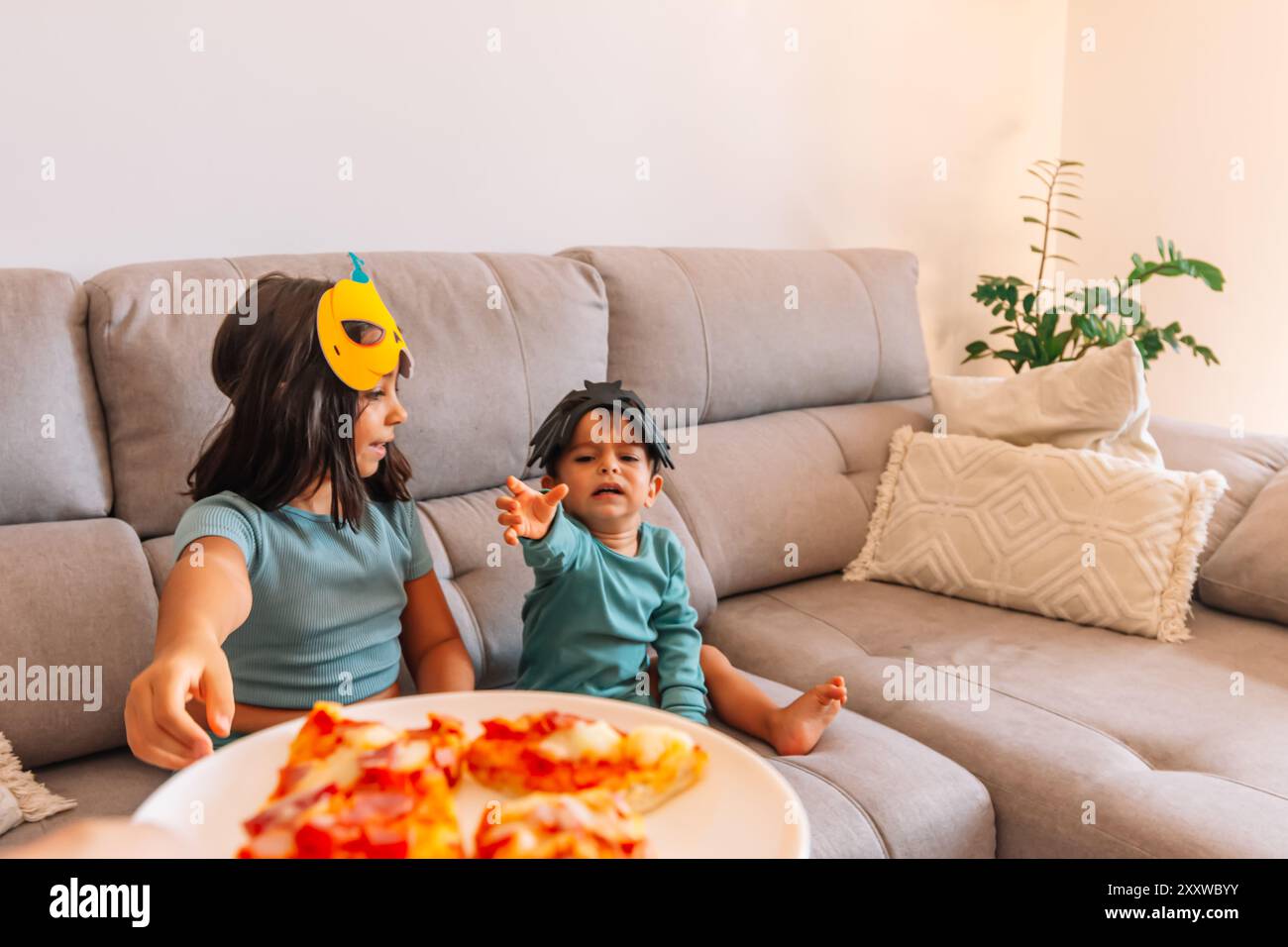 Enfants en costumes d'halloween mangeant de la pizza Banque D'Images