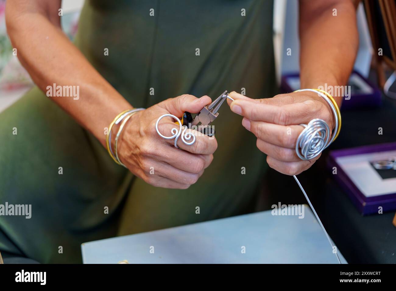 Femme hispanique méconnaissable dans ses années 50 Crafting boucles d'oreilles à son stand de rue vendant des bijoux en fil d'aluminium faits à la main Banque D'Images