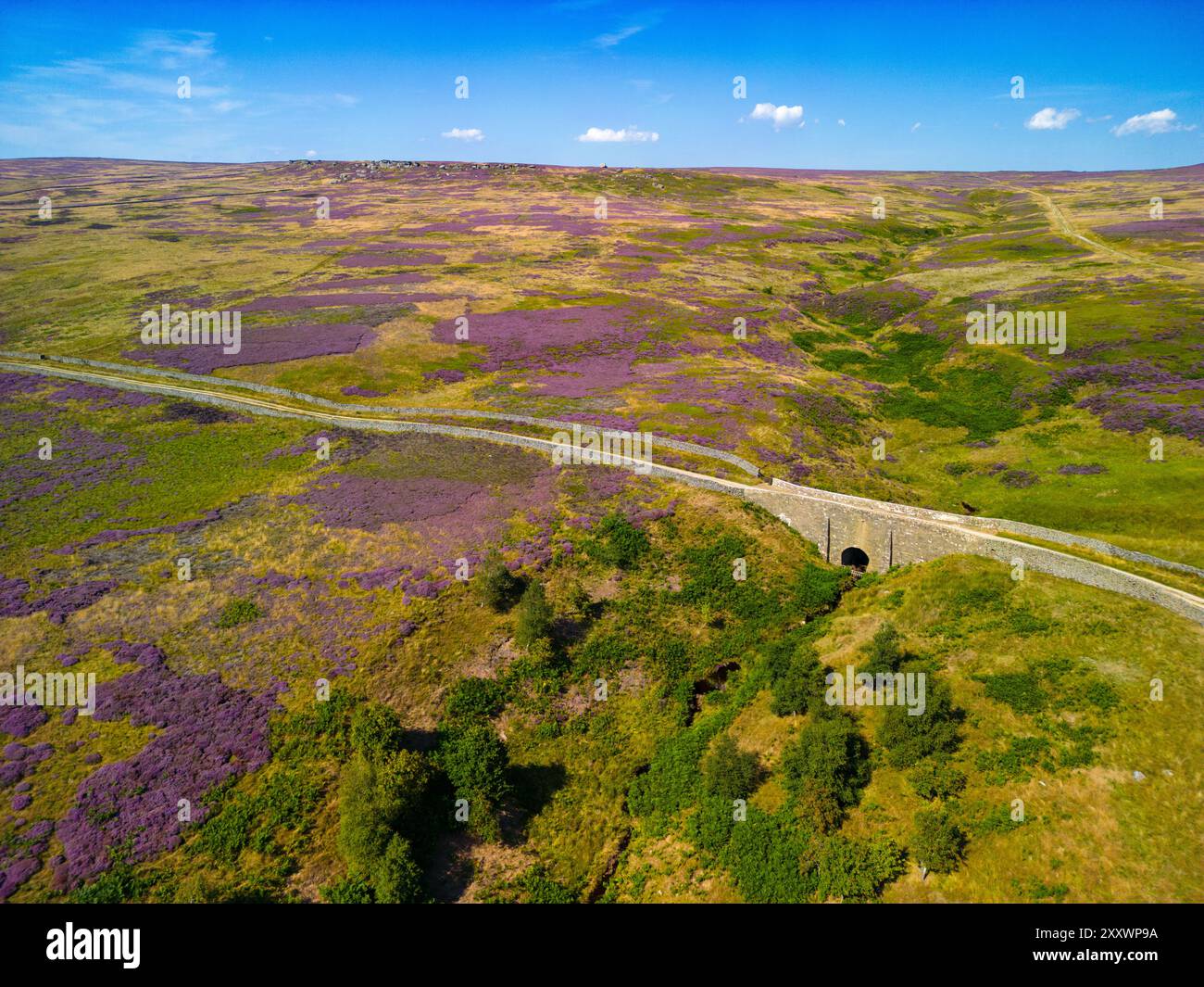 Un drone capture la vue imprenable sur l'ancien pont sur Kirkby Malzeard Moor, mettant en valeur de vastes champs de bruyère sous un ciel clair. Banque D'Images