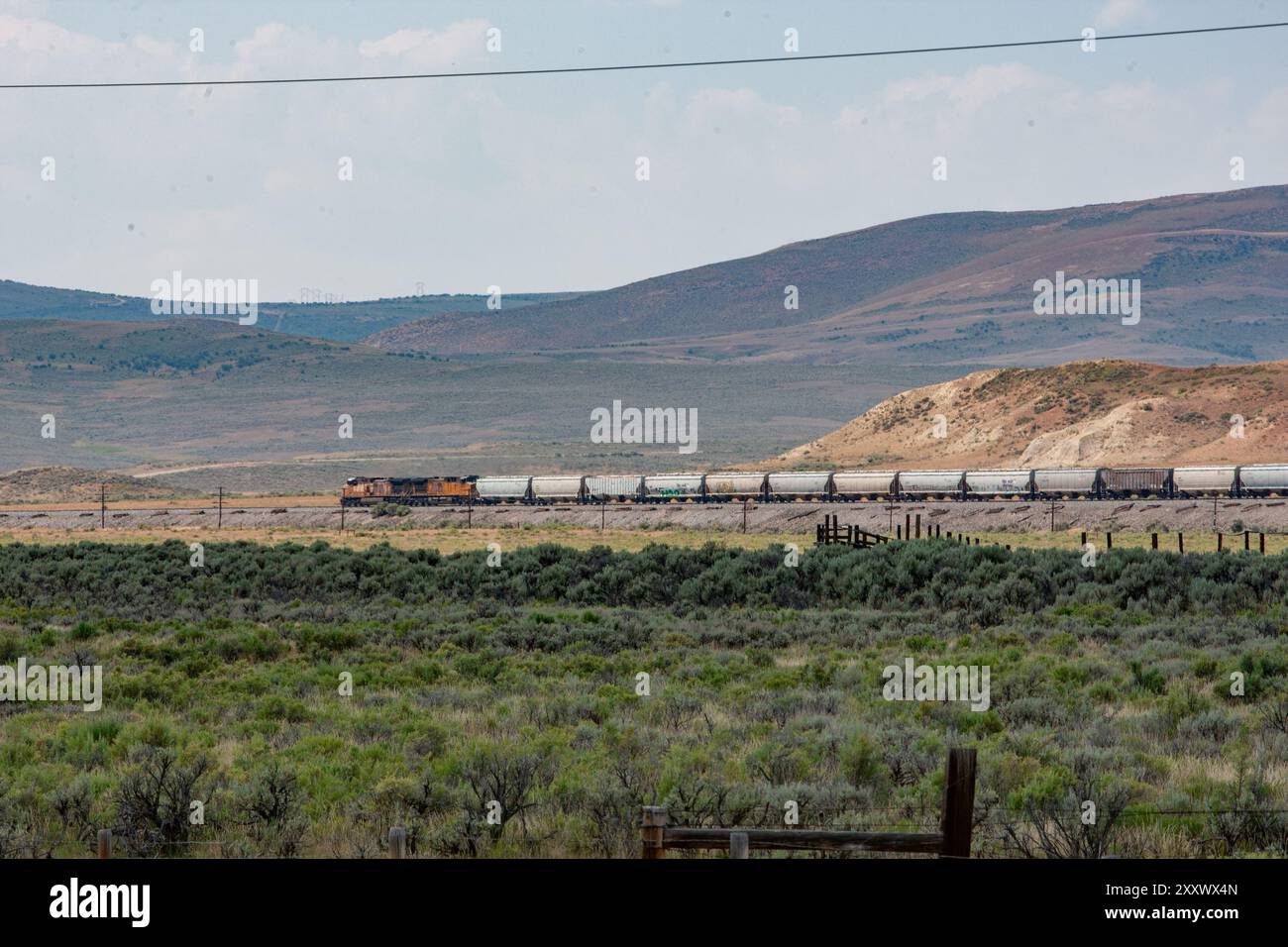 Une locomotive et son train défilent devant Fossil Butte National Monument dans le Wyoming, créant un contraste saisissant avec le monument en toile de fond Banque D'Images
