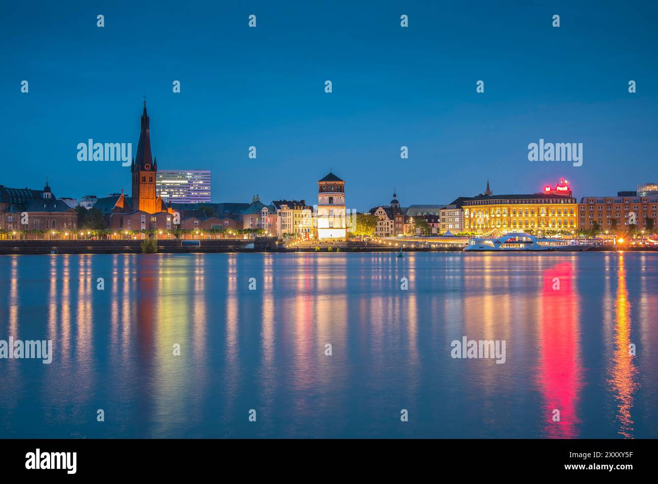 Vue de nuit de Düsseldorf-Oberkassel vers la vieille ville avec 'Rheinuferpromenade', l'église Lambertus et le musée 'Schlossturm'. Banque D'Images