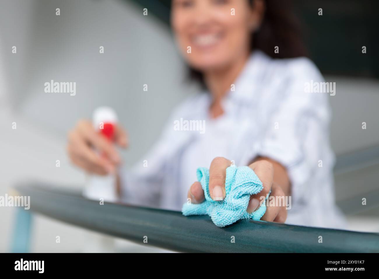 femme au foyer nettoyant les rampes d'escalier avec un chiffon à la maison Banque D'Images