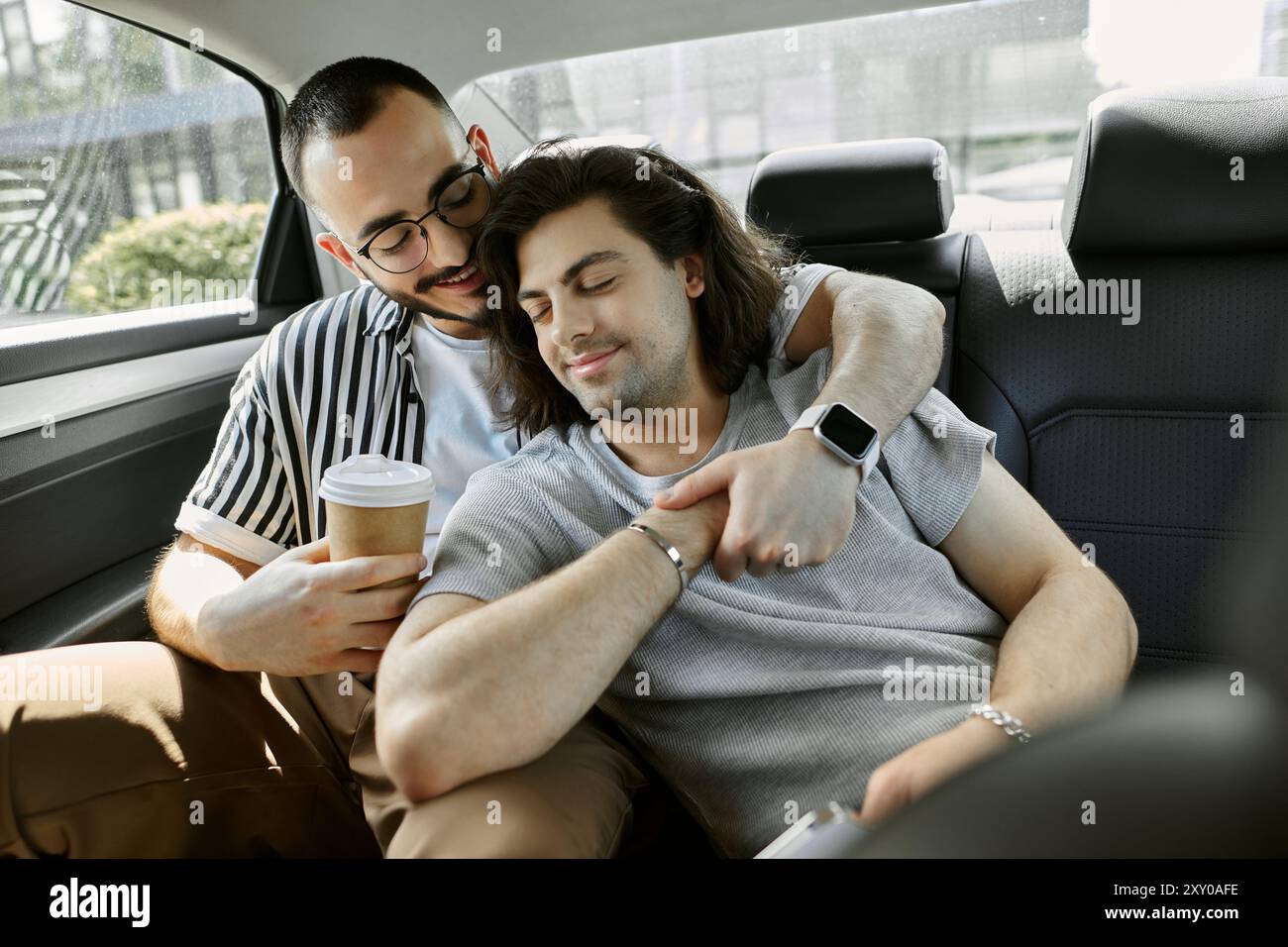 Couple en voiture, l'un tenant le café, l'autre reposant la tête sur l'épaule Banque D'Images