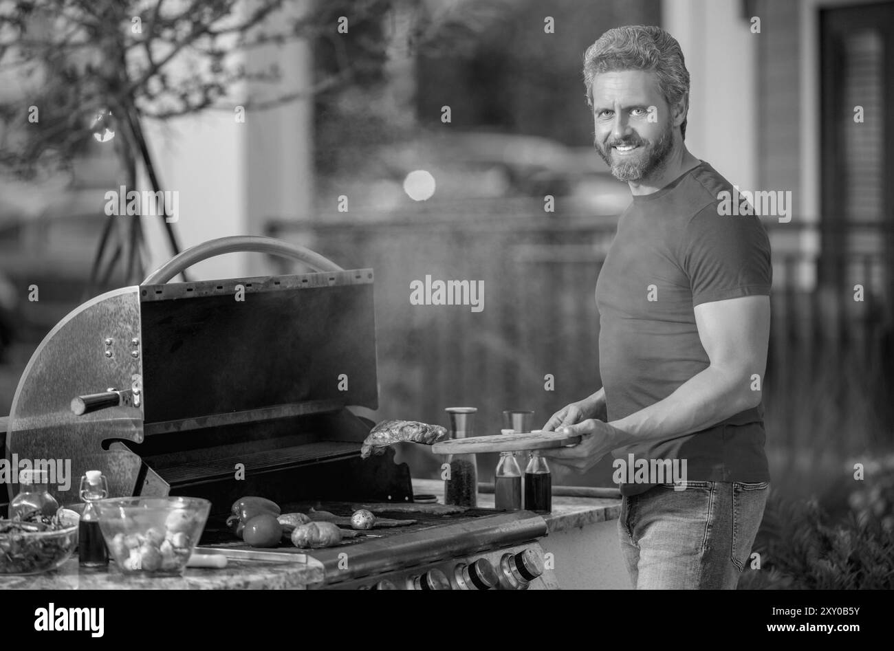 Hommes cuisinant le steak sur barbecue grill dans la cour. Cuire à un gril barbecue en préparant de la viande. Banque D'Images