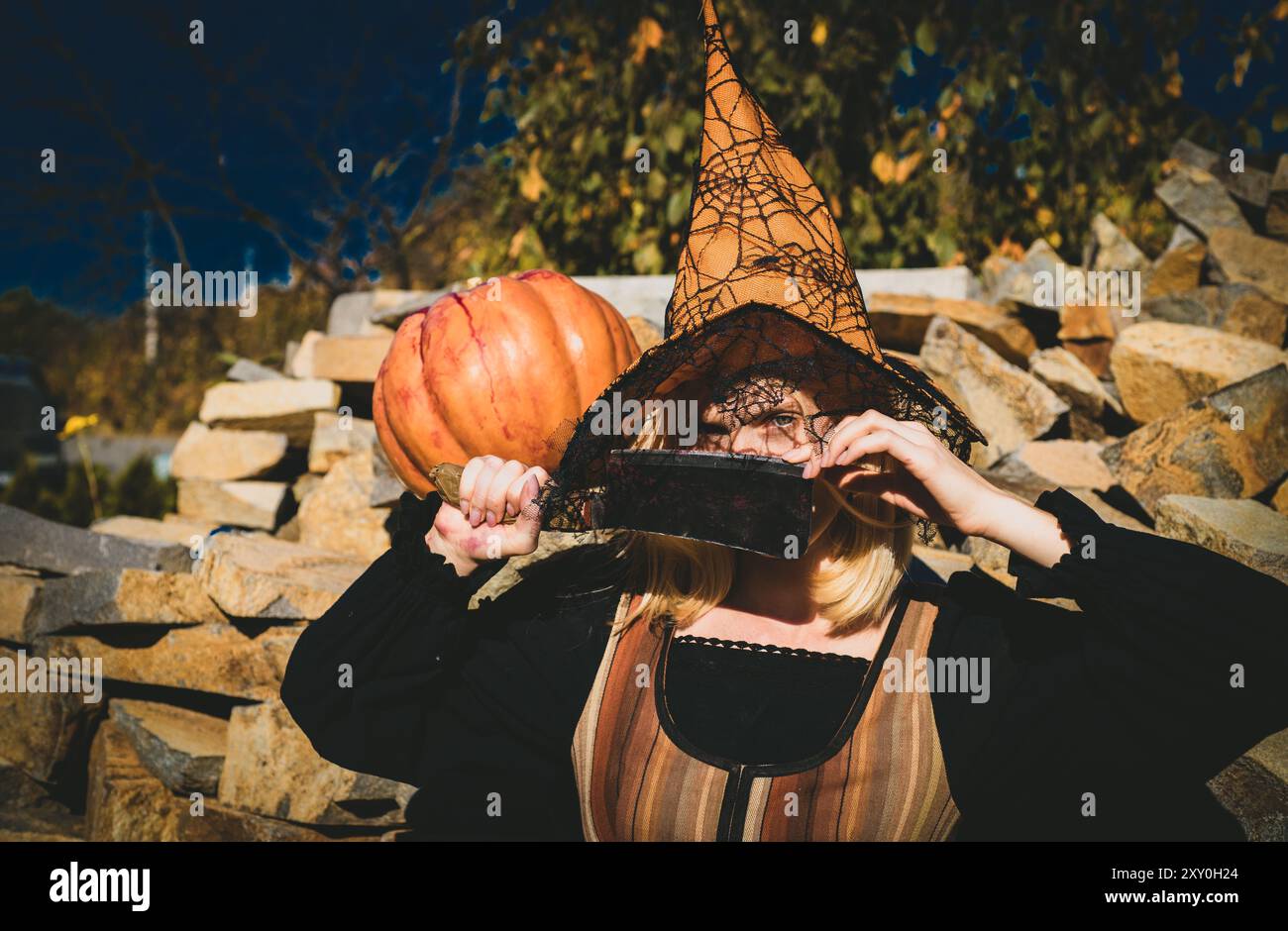 Jeune femme émotive en costume d'halloween lors de la fête d'halloween. Belle jeune femme en sorcières chapeau avec citrouille. Fête d'Halloween. Image de Banque D'Images