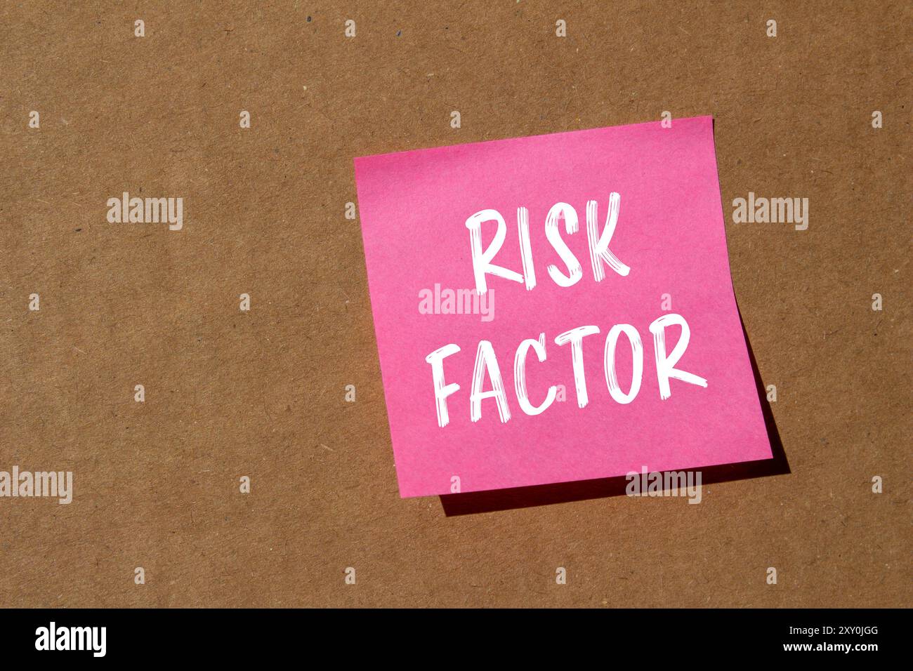 Message de facteur de risque écrit sur du papier rose avec fond en carton. Symbole de facteur de risque conceptuel. Copier l'espace. Banque D'Images