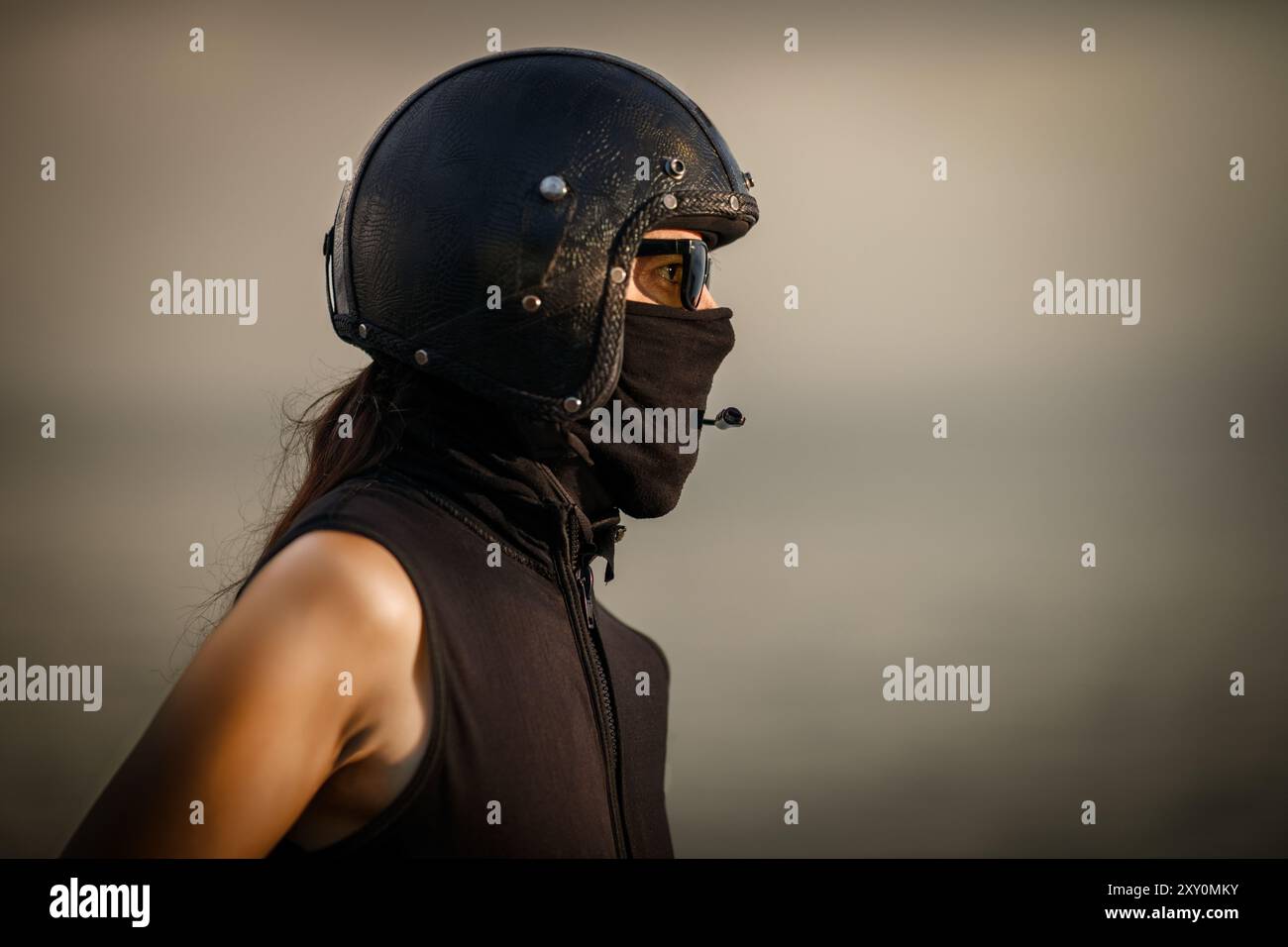 Portrait d'un motard portant un casque en cuir, des lunettes et un couvre-visage, prêt pour la balade. Le cavalier est habillé de noir, donnant un dur et myst Banque D'Images