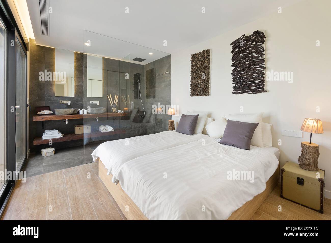 Une chambre moderne décorée avec goût avec un mur de verre qui intègre la salle de bain, améliorant le sens de l'espace bois et pierre éléments contri Banque D'Images